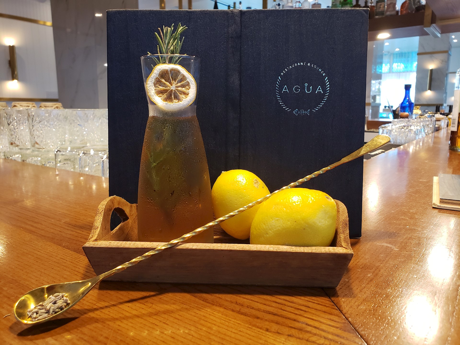 brown-cocktail-and-two-lemons-in-a-wood-tray-with-a-menu-in-the-background