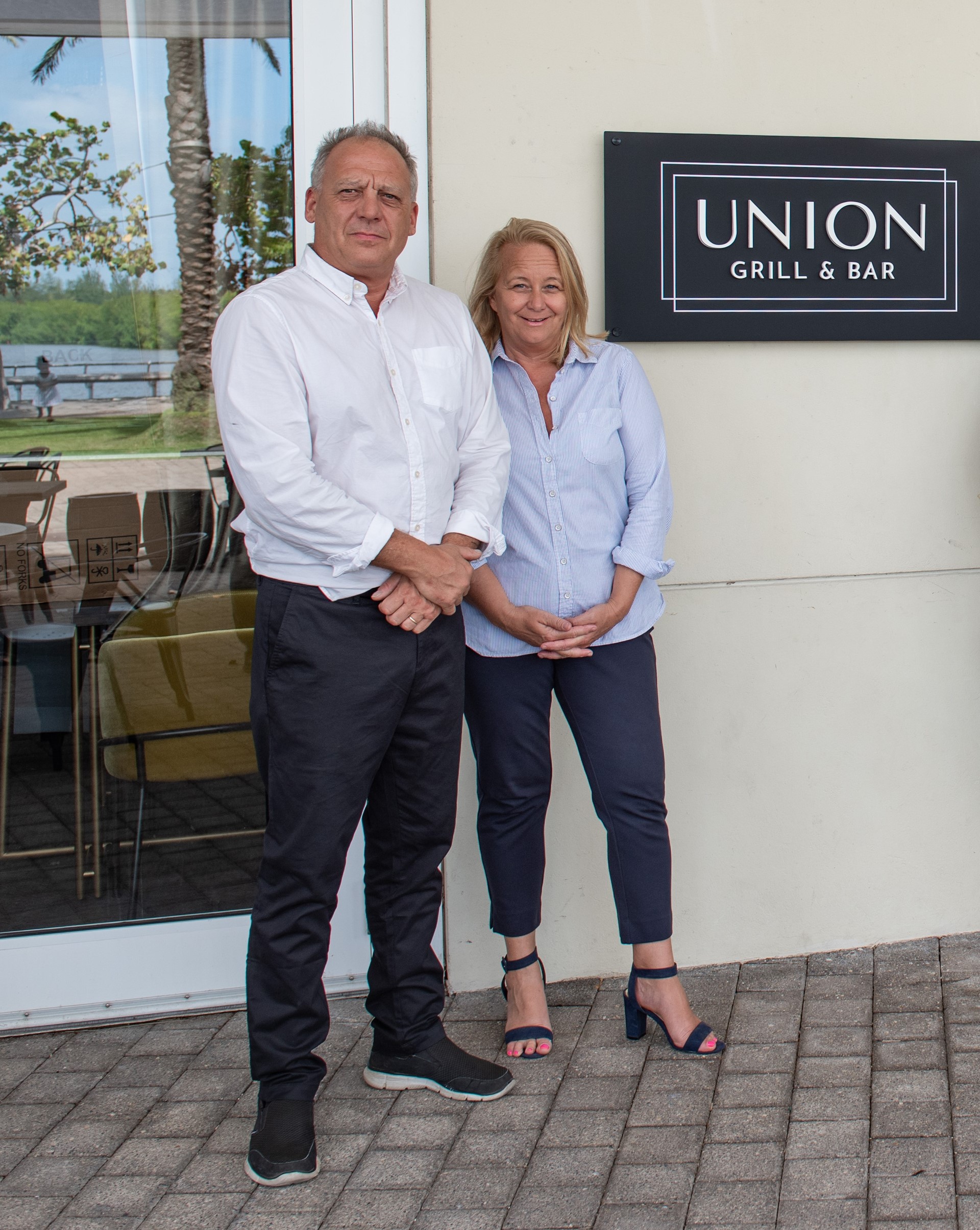restaurant owners in front of signage