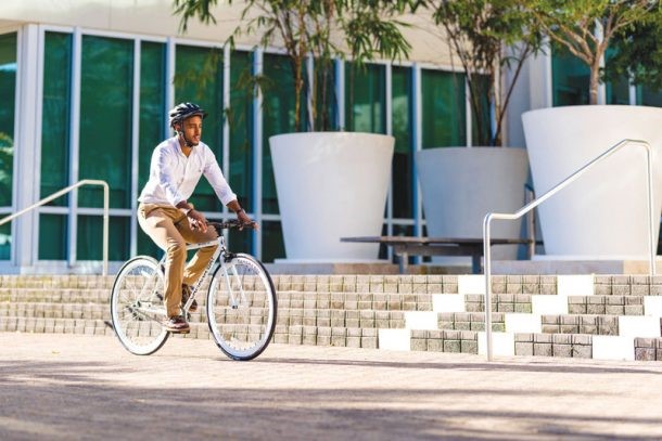 man-riding-a-bicycle-with-a-helmet-on-in-front-of-a-staircase