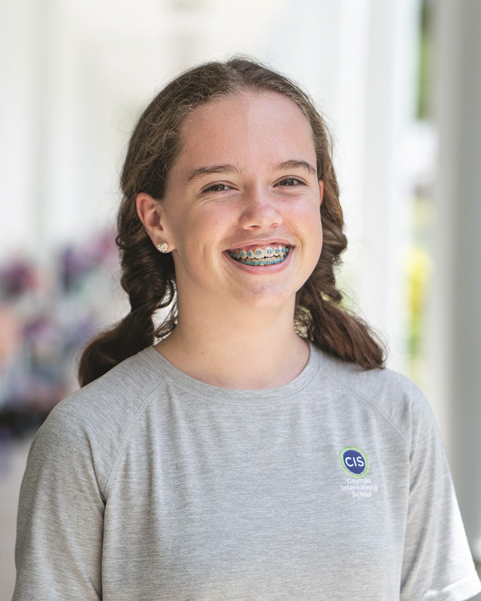 Caucasian pre-teen girl with brown hair and braces smiles at the camera