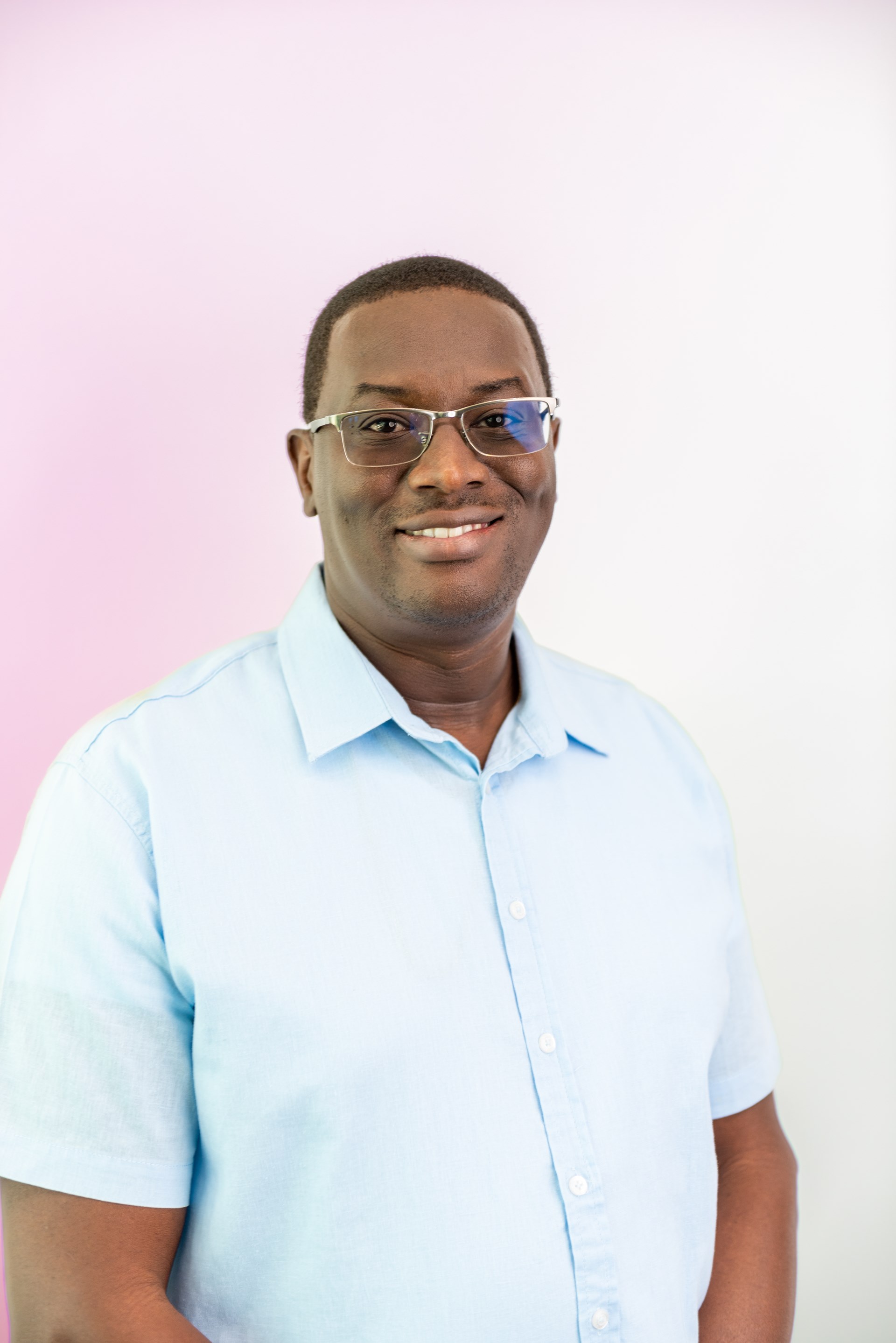 black man with glasses smiles at camera