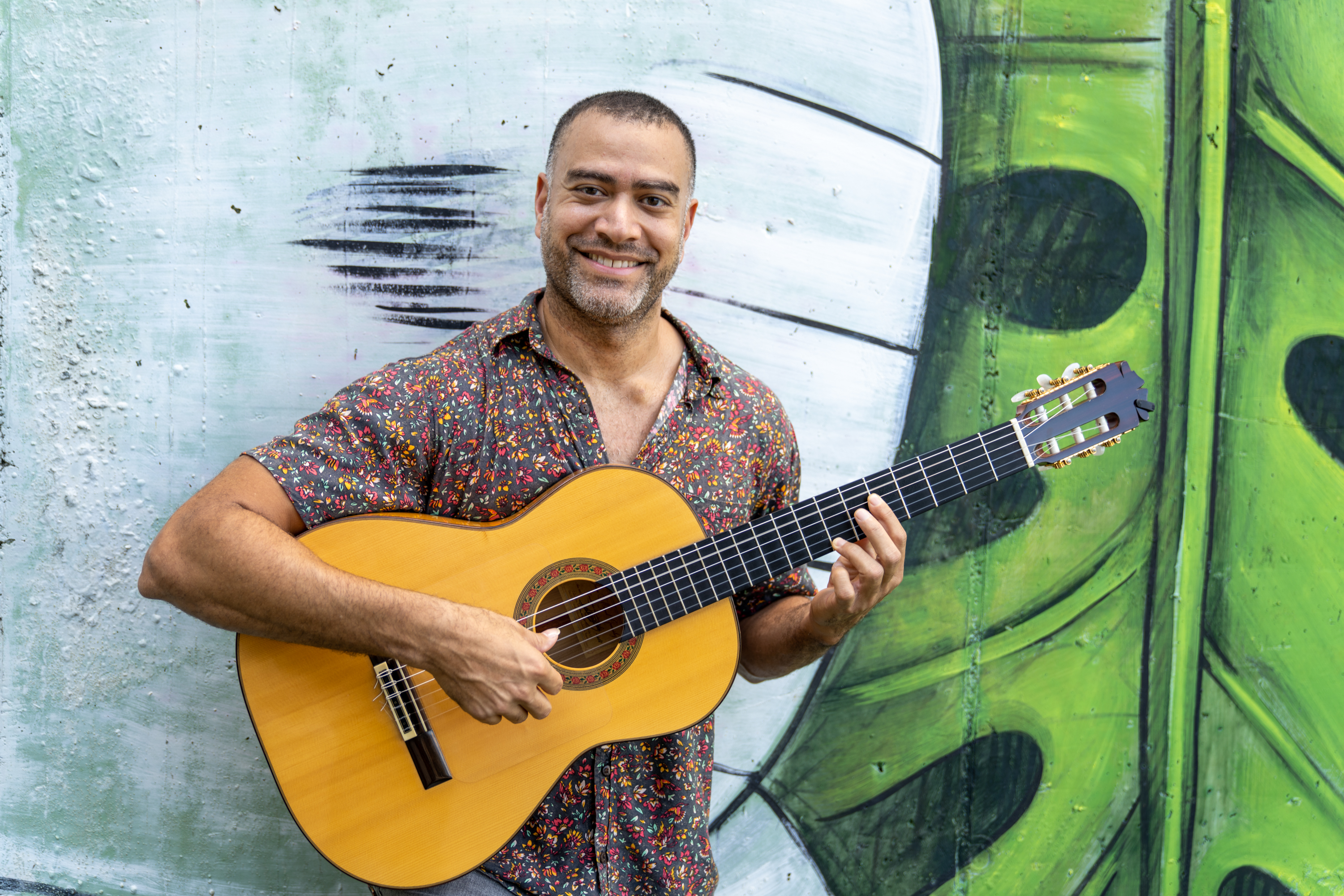 Man holding guitar smiling at camera