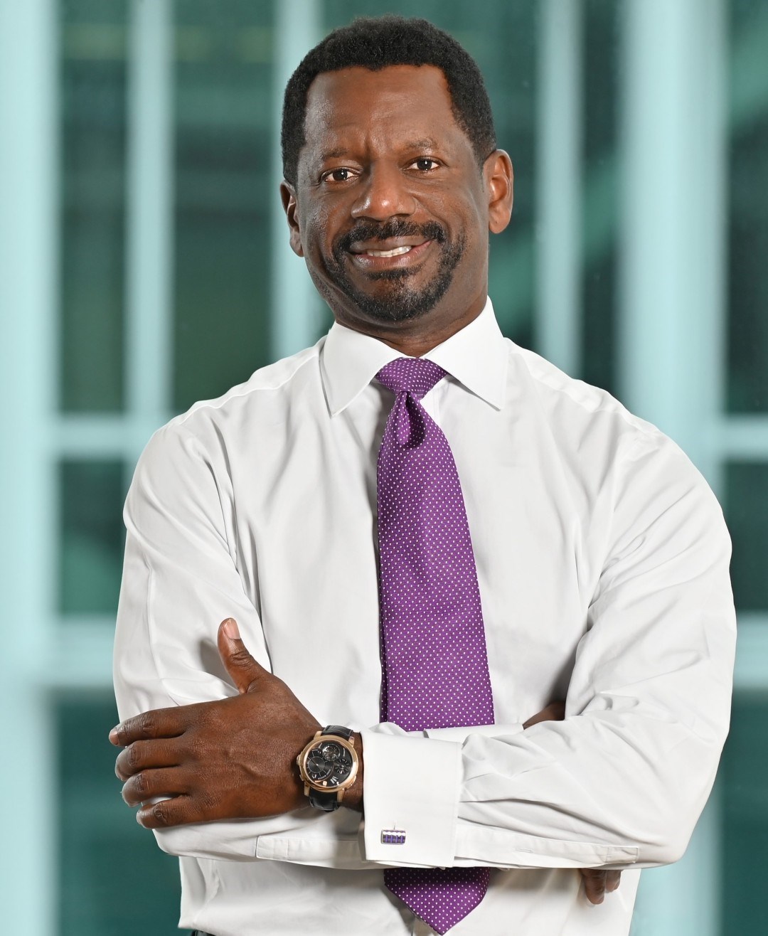 Black man with arms crossed smiling at camera