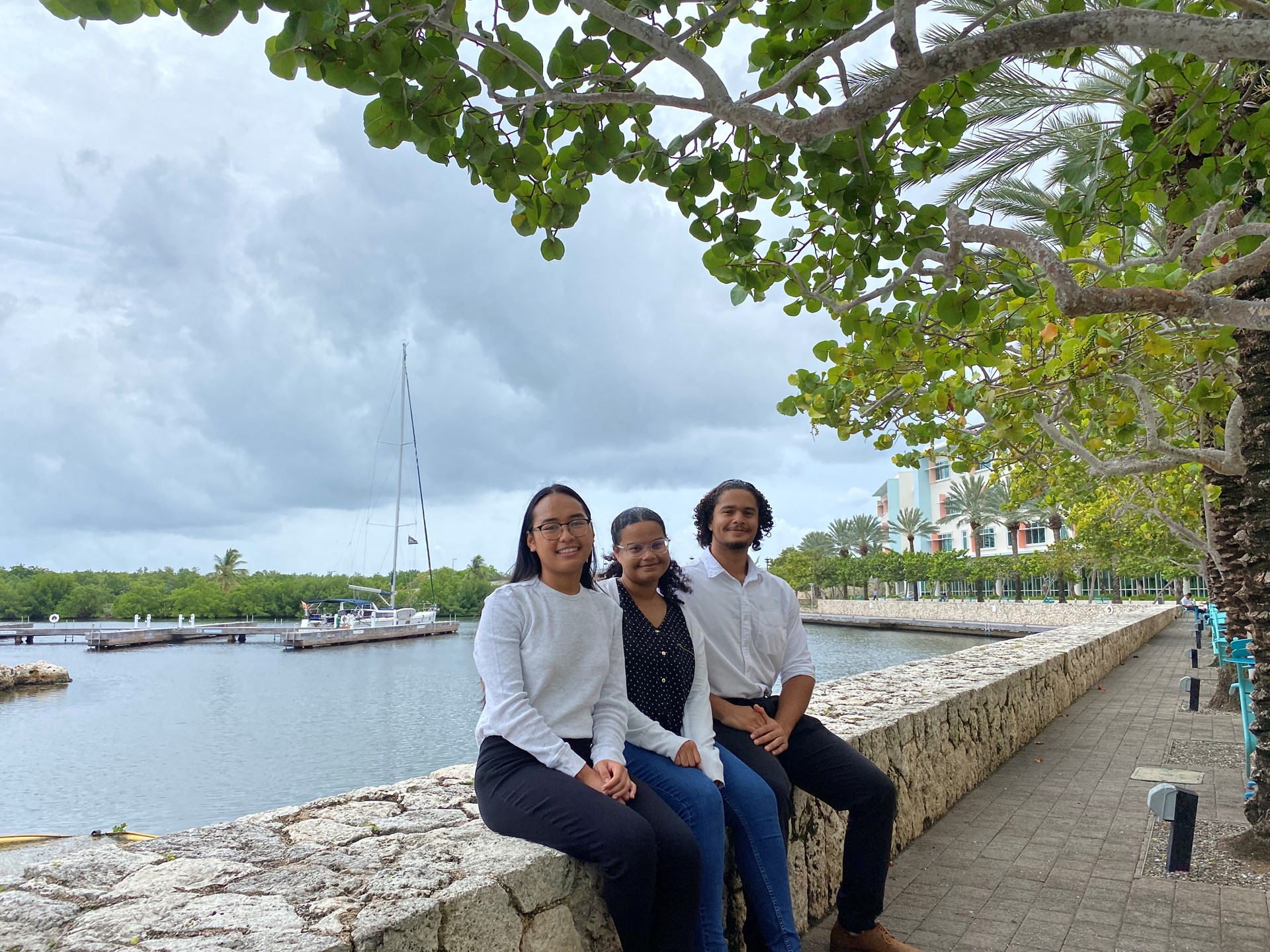 three summer interns sitting on outside wall