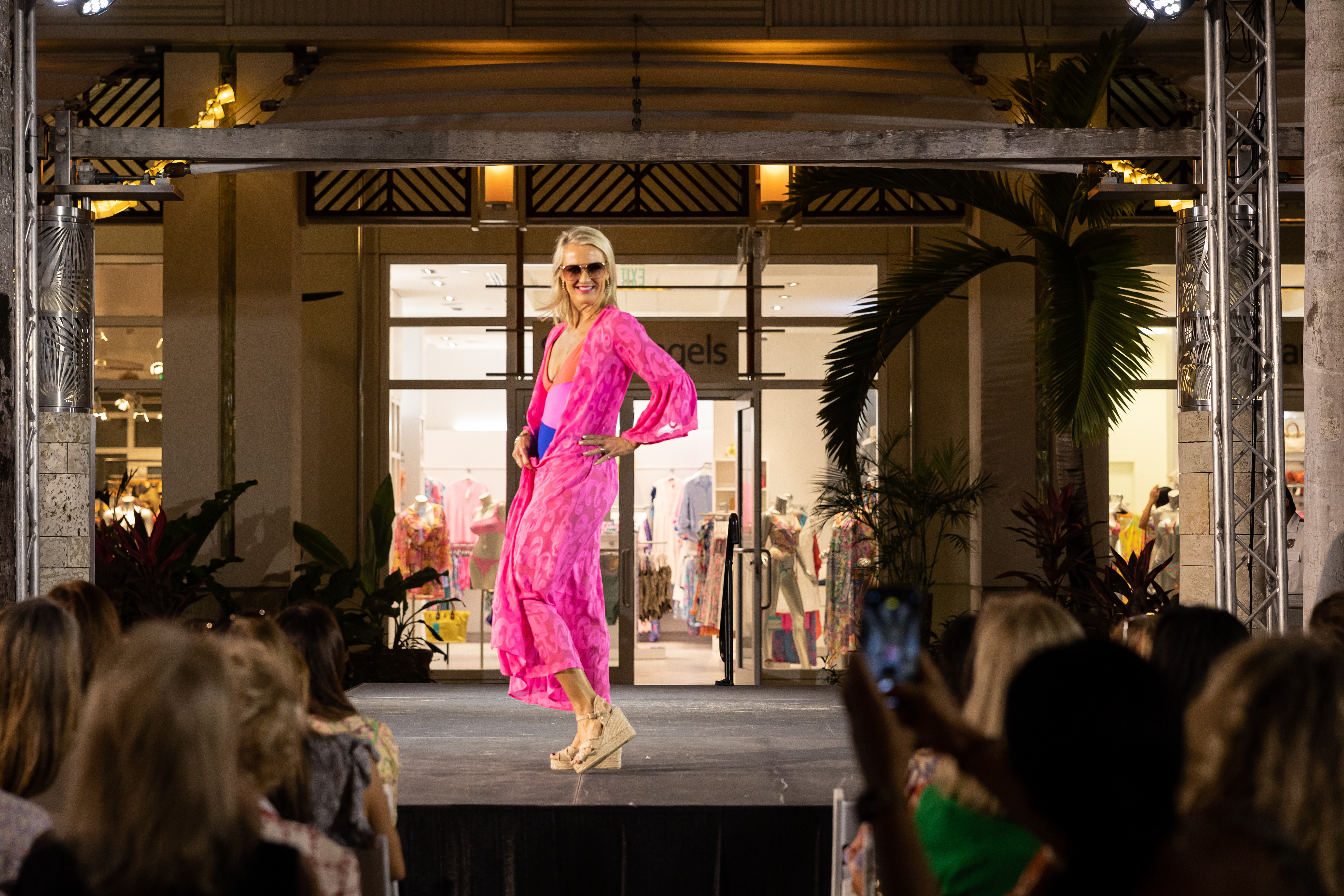 Woman dressed in pink outfit modeling on stage. 